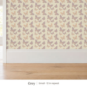 Butterfly Kisses Grey peel and stick wallpaper, small 12 in repeat, above a white baseboard and oak floor