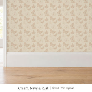 Butterfly Kisses Cream, Navy & Rust peel and stick wallpaper, small 12 in repeat, above a white baseboard and oak floor