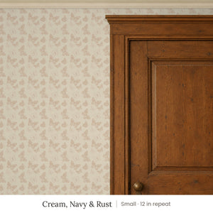 Butterfly Kisses Cream, Navy & Rust peel and stick wallpaper, small 12 in repeat, beside a wood door