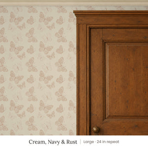 Butterfly Kisses Cream, Navy & Rust peel and stick wallpaper, large 24 in repeat, beside a wood door