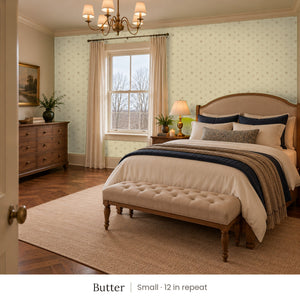 Celia Butter peel and stick wallpaper, small 12 in repeat, in a bedroom with an upholstered bed and a tufted bench
