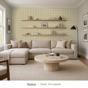Zelda Butter peel and stick wallpaper, small 12 in repeat, in a family room with a sectional sofa and open shelves