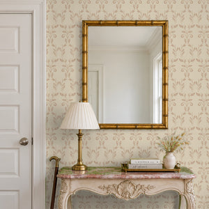Quince Blush peel and stick wallpaper in an entry with a gold mirror and a carved console