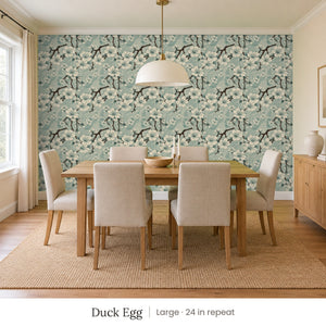 Sakura Duck Egg peel and stick wallpaper, large 24 in repeat, in a dining room with a wood table and upholstered chairs