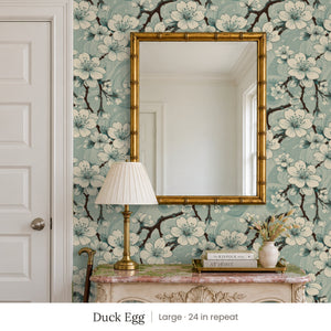 Sakura Duck Egg peel and stick wallpaper, large 24 in repeat, in an entry with a gold mirror and a carved console